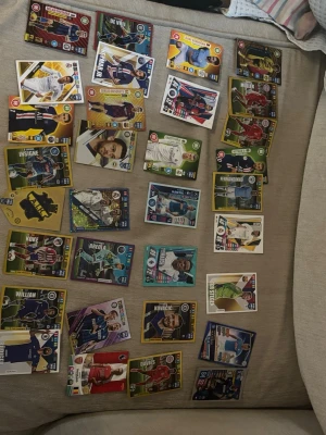 Samling fotbollssamlarbilder - Säljer en samling fotbollssamlarbilder med olika spelare från flera internationella lag. Korten har färgstarka designer i gult, grönt, blått och rött, och visar spelare i matchställ. Perfekt för dig som gillar att samla på fotbollskort eller vill byta med vänner.