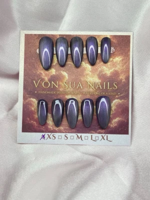 Velune (XS);Medium Almond - Handgjorda press-on naglar i en snygg svart-lila färg med cateye skimrande finish. Naglarna har en medium lång almondform och kommer i XS: 14 mm, 11 mm, 11,5 mm, 10 mm, 8 mm. Perfekt för dig som vill ha en unik och trendig look.