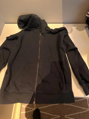 Mörkblå zip hoodie med fickor - Mörkblå hoodie med dragkedja framtill och två stora fickor. Klassisk huva och ribbade muddar vid ärmslut och nederkant. Perfekt för en avslappnad stil och enkel att matcha med andra plagg.