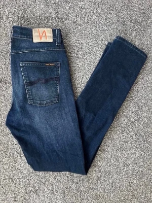 Mörkblå jeans från Nudie Jeans (Lean Dean) - Snygga mörkblå jeans från Nudie Jeans modellen är Lean Dean med klassisk femficksdesign och diskret logga på bakfickan. Jeansen  är tillverkade i mjuk bomull med lite stretch för extra komfort. W30 L32