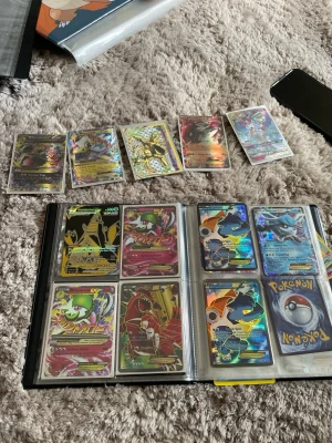 Pokémonkort samling i pärm - Stor samling Pokémonkort i pärm med flera holografiska och full art-kort. Blandade motiv och färger, många populära Pokémon och specialkort. Perfekt för dig som vill utöka din samling eller börja samla. Alla kort sitter i plastfickor i en svart pärm. Kan sälja allt men även kort för sig, hör av dig med prisförslag 