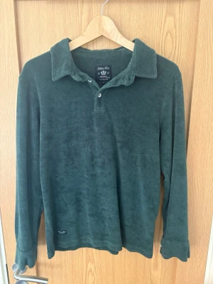 Mörkgrön långärmad collegetröja - Mysig mörkgrön collegetröja från Stenströms i mjuk frottéliknande material. Tröjan har klassisk krage, knäppning vid halsen och långa ärmar. Perfekt för en avslappnad och stilren look.