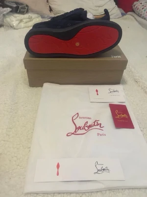 Mörkblå sneakers från Christian Louboutin - Snygga mörkblå sneakers från Christian Louboutin med klassisk röd sula. Storlek 42. Min bror tyckte inte om den alls och den satt lite för tajt  