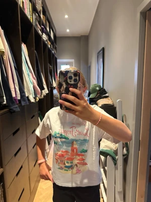 Vit t-shirt med Saint-Tropez tryck - Säljer en vit t-shirt med färgglatt tryck av Saint-Tropez och texten 'See you in Saint-Tropez' på framsidan. T-shirten har korta ärmar och en klassisk passform. Perfekt för dig som gillar coola motiv och somriga vibes.
