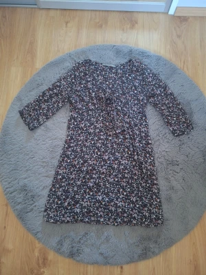 Blommig klänning från Zara Basic - Mörkblommig klänning från Zara Basic med små vita, rosa och röda blommor. Klänningen har trekvartsärm, v-ringning och en avslappnad passform. Perfekt för dig som gillar en feminin och bekväm stil.