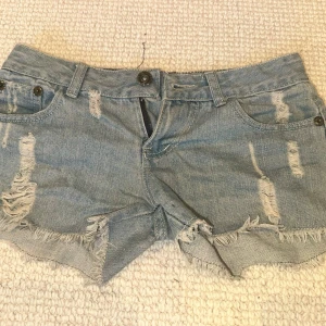 Ljusa slitna jeansshorts - Säljer ett par ljusblå jeansshorts med slitningar och råa kanter. Köpta second hand i Spanien!! Skriv gärna vid frågor och hör av er vid intresse!!🥰