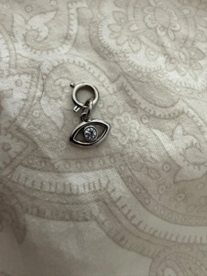 Barlock  - Barlock i silverfärgad metall med ett öga  med hänge till fästa i barlock armband/Halsband aldrig andvänt från Edblad 