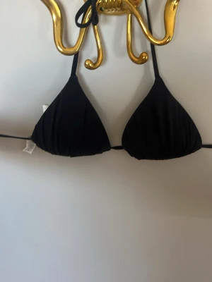 Svart trekantsbikini med knyt - Snygg svart trekantsbikini med knyt i nacken och ryggen. Klassisk och stilren modell som passar perfekt till sommaren! Använd en gång