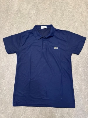 Lacoste piké  - Säljer en marinblå Lacoste piké-tröja i nyskick till riktigt bra pris. Säljer dom enbart för att rensa lite hemma och att jag behöver bli av med de så snabbt som möjligt. Kontakta mig vid frågor eller funderingar.