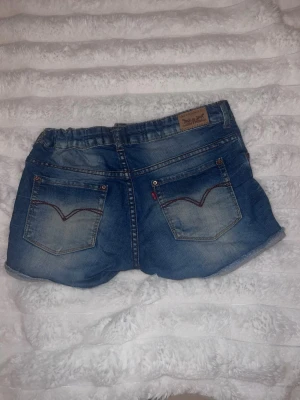 Levi's jeansshorts - Snygga blå jeansshorts från Levi’s. Shortsen har slitna detaljer. Mycket bra skick. Öppen för prisförslag och frågor💕💕