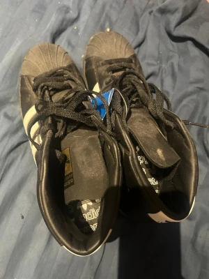 Adidas skor - Säljer ett par svarta Adidas skor med vita ränder på sidorna och snörning. Kostade 1500kr. Har inte använt dom någonting men har inte kvar någon prislapp. Storlek 44. Kom gärna med prisförslag eller frågor🤗(katt finns i hemmet)