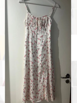 Vit blommig långklänning  - Söt långklänning i vitt med små rosa blommor och gröna blad. 