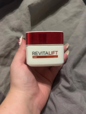 Revitalift dagkräm 50ml - Revitalift dagkräm i en vit burk med rött lock. Krämen är uppstramande och anti-rynk, perfekt för dig som vill ha en slätare och fastare hud. Förpackningen rymmer 50 ml och är enkel att använda med skruvlock.