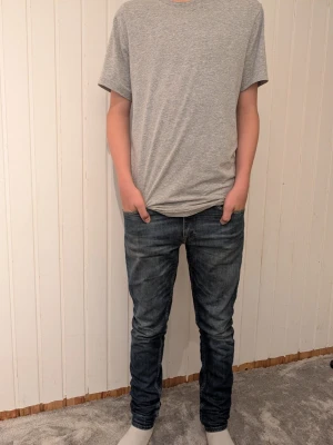 Mörkblå slim fit jeans herr - Snygga mörkblå slim fit jeans med lätt tvättad look och klassiska fem fickor. Jeansen har normal midja och smal passform hela vägen ner. Perfekta för dig som gillar en modern och enkel stil. 