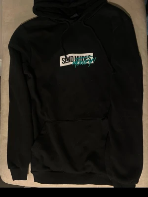 Svart hoodie med tryck 'Send Money!' - Svart hoodie med huva och magficka. På bröstet finns ett tryck med texten 'SEND NUDES' där 'NUDES' är överstruket och ersatt med 'MONEY!' i turkos. Klassisk streetwear-stil med huva. Perfekt för dig som gillar statement-plagg. Perfekt skick! Storleken upplevs lite större än XS skulle mer säga S utifrån hur den passar på mig! 😃 spana även in mina andra plagg! 🌷