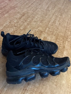 Svarta Nike Air VaporMax Plus - Säljer ett par Nike Air VaporMax Plus i svart. Använda men i bra skick utan skador. Normalt slitage förekommer, men skorna ar val omhändertagna och har mycket kvar att ge.