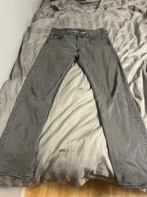 Grå Levis 501:or jeans - Säljer ett par grå jeans med rak passform och klassisk femficksdesign. Jeansen har normal midja och bälteshällor. Materialet är denim i bomull och färgen är en snygg tvättad grå. Pris kan diskuteras 
