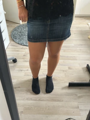 Mörkblå jeanskjol med fickor - Säljer en mörkblå jeanskjol i kort modell med två stora bakfickor och synliga sömmar. Kjolen har en klassisk denimlook och passar perfekt till både vardagsoutfits och mer uppklädda stilar. Enkel att matcha med olika toppar och skor.