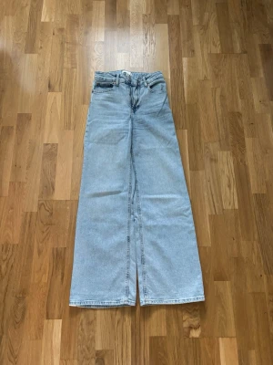 Ljusblåa vida jeans  - Säljer ett par ljusblå vida jeans från H&M i bra skick. Medel/hög midja