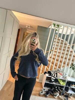 Mörkblå stickad tröja - Mysig mörkblå stickad tröja med rund halsringning och långa ärmar. Tröjan har en avslappnad passform och är tillverkad i ett mjukt, fluffigt material som känns skönt mot huden. Perfekt att bära till jeans eller mjukisbyxor.