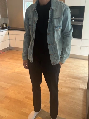 Ljusblå klassisk jeansjacka - Säljer en ljusblå jeansjacka i klassisk modell från Tiger of Sweden. Jackan har en avslappnad passform och tidlös design som passar till det mesta. Storlek XL! 