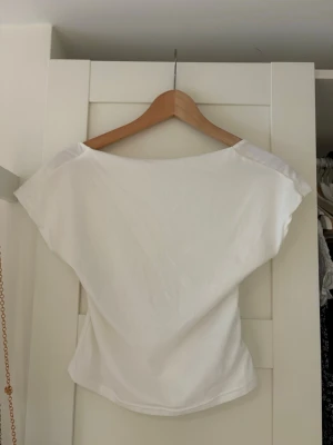 Vit croppad topp med öppen rygg - Säljer en vit croppad topp med korta ärmar och en djup öppen rygg. Toppen har en enkel och clean look, perfekt för dig som gillar minimalistisk stil. Tillverkad i mjukt bomullstyg som känns skönt mot huden.