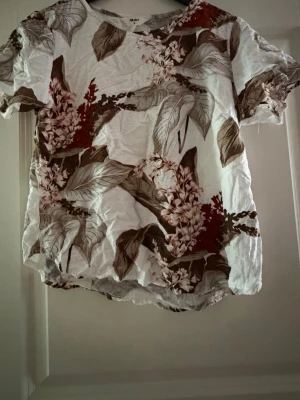 Blommig topp från OBJECT - Säljer en vit topp från OBJECT med blommigt mönster i beige och bruna blommor. Har vanligtvis Xs och den är för liten på mig 