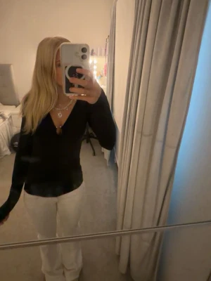 Svart långärmad v-ringad topp - Snygg svart långärmad topp med djup v-ringning. Toppen har en slim passform och är perfekt att styla med smycken. Enkel och stilren design som passar till många olika looks.