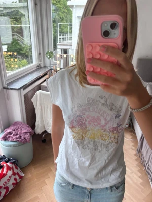Vit t-shirt med färgglatt tryck Zadig & Voltaire - Vit t-shirt från Zadig & Voltaire med ett färgglatt blommigt tryck i rosa, gul och grå toner på bröstet. T-shirten har rund halsringning och korta ärmar. Perfekt för dig som gillar en avslappnad men ändå cool stil.