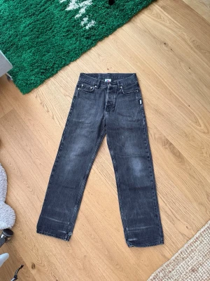 Svarta district fortysix jeans (Fade) - Säljer ett par svarta jeans med rak passform och tvättad finish. Jeansen har klassisk femficksdesign, silverfärgade nitar och knapp, samt normal midja. Materialet är denim i bomull och de har en avslappnad vibe som passar till det mesta.