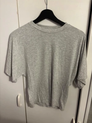 Ljusgrå topp - En ljusgrå topp som är tajt i midjan men lös uppe.