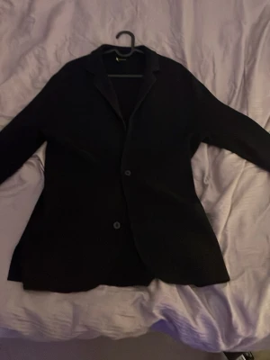 Stickad kavaj från Massimo dutti  - En stilren svart kavaj med två knappar framtill och klassisk krage. Passar perfekt till en dressad look och har en rak, något längre passform. Materialet ser ut att vara mjukt och följsamt, vilket ger en bekväm känsla. Enkel och tidlös design.