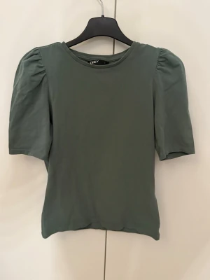 Grön topp med puffärm från ONLY - Snygg grön topp från ONLY med puffade axlar och rund halsringning. Perfekt till jeans eller kjol för en trendig look.