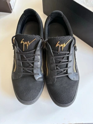 Giuseppe zanotti - Riktigt snygga och clean skor från Giuseppe zanotti, helsvarta skor med riktigt fräscha gulddetaljer på dragkedjorna och märket på plösen, använda ett par gånger och skorna är i bra skick, skriv gärna vid funderingar.
