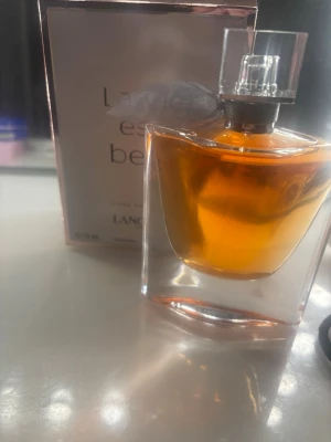 La Vie Est Belle parfym 75ml - La Vie Est Belle från Lancôme är en elegant parfym i en genomskinlig glasflaska med en mjukt orange doftvätska. Flaskan har en silvrig dekor vid halsen och kommer med originalkartong. Volymen är 75 ml.