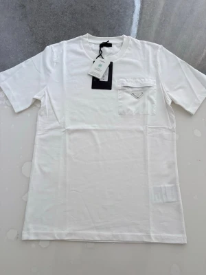 Prada t shirt  - Hej! Säljer en jätte fin T-shirt som är i väldigt bra skick inga problem alls Väldigt fin till sommaren Storlek S (lite baggy, kan även passa M) Påse och tags ingår Skriv gärna vid intresse ❤️💯