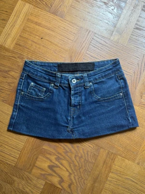 Kort jeanskjol / minikjol  - En jeanskjol som jag har sytt från ett par jeans. Midjemått: 37 cm. Längd: ca 25 cm. Storlek står ej men skulle säga att den passar en XS/S.