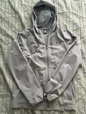 Under Armour windbreaker inga bud - Säljer en fin windbreaker jacka från underarmour, bara stått i garderoben sen jul, den är använd några gånger men inte mer än så.