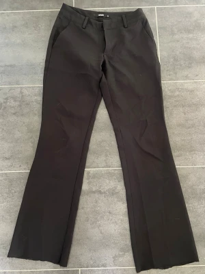Svarta lågmidjade kostymbyxor  - Svarta lågmidjade kostymbyxor från bikbok i storlek 34 som är avklippta längst ner. Passar mig som är 155 cm. Säljer även ett par likadana i storlek 36. 