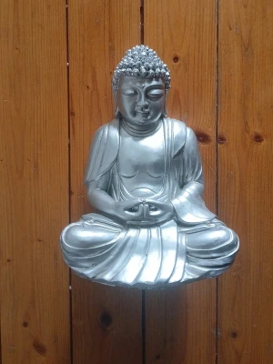 Silverfärgad Buddha-staty - Säljer en stilren Buddha-staty i silverfärgad metall. Figuren sitter i meditationsställning med detaljerad utformning av drapering och hår. Perfekt som inredningsdetalj för ett lugnt och harmoniskt rum.