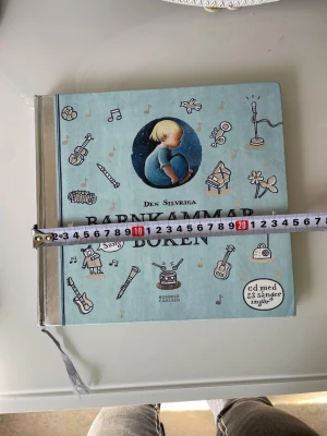 Den silvriga Barnkammarboken - En stor, kvadratisk barnbok med blått omslag och silvrig rygg. Boken är rikt illustrerad med musikaliska motiv och innehåller klassiska barnvisor och godnattsagor. Perfekt för högläsning och sångstunder. Bok från Bonnier Carlsen.