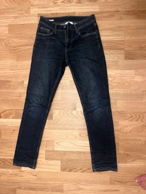 Vailent Jeans Mörkblå - Snygga mörkblå slim fit jeans med klassisk femficksdesign och smala ben. Jeansen har en stilren look med subtila slitningar och kontrastsömmar. Perfekta för dig som gillar en enkel men trendig stil. Materialet är bomull med lite stretch.
