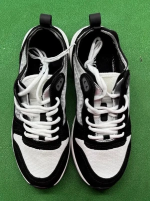 Svarta och vita  sneakers - Snygga sneakers i svart och vitt med mesh och mockadetaljer. Skorna har vita snören, svart sula och tydlig logga bak på hälen. Modern design med sportig känsla och kontrasterande materialval.