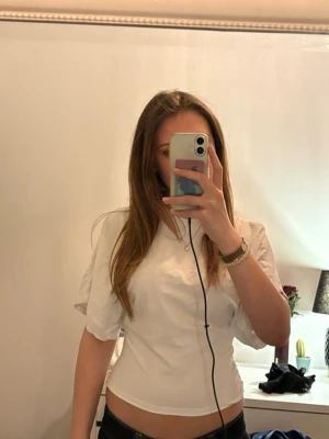 Vit croppad t-shirt som sitter åt i midjan - Säljer en vit t-shirt från nelly med en och rund hals och åtsittande runt midjan. T-shirten har en enkel och clean look som passar perfekt till allt men säljer då jag sällan använder den😇