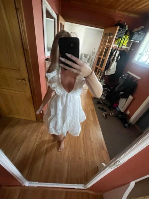 Vit kort klänning med snörning - Söt vit kortklänning med volangdetaljer, djup v-ringning och snörning i ryggen. Klänningen har puffiga korta ärmar. Hade denna på min student 💞💞