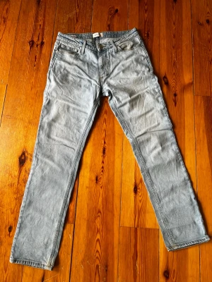 Ljusgrå raka jeans - Säljer ett par ljusgrå jeans med rak passform och klassisk femficksdesign. Jeansen har normal midja och är tillverkade i ett mjukt denimtyg. Perfekta för en avslappnad och stilren look.