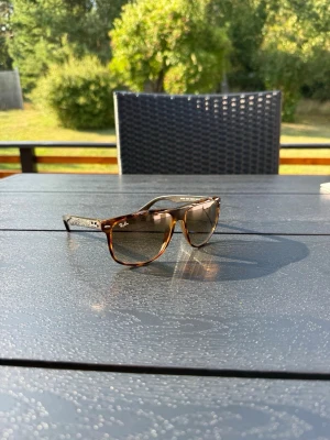 Ray-band boyfriend solglasögon - Snygga solglasögon från Ray-Ban i klassisk wayfarer-modell. Bågarna är bruna med sköldpaddsmönster och glasen är tonade i brunt. Perfekta för soliga dagar.