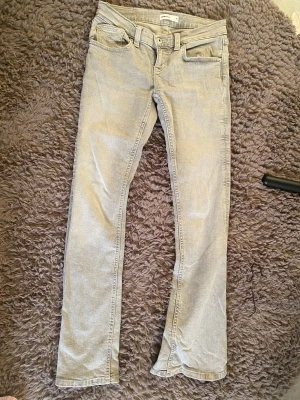 Ljusgrå raka jeans och mörk blåa jeans - Säljer ett par ljusgrå jeans och mörkblåa jenas med rak passform och klassisk femficksdesign. Jeansen har bälteshällor och knappgylf. Perfekta för en avslappnad och stilren look. Materialet ser ut att vara bomullsdenim.