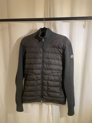 Moncler cardigan  - Grå moncler cardigan, grymt skick, storlek 2 vilket motsvarar m, äkta såklart, köpes ny för 1,5 år sedan men finns inget kvitto kvar. Ändast liten deffekt i armbågen där det är litet hål, tänks inte på.