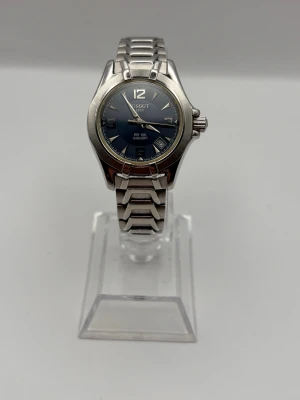 Tissot silverfärgad klocka blå urtavla - Stilren klocka från Tissot i rostfritt stål med silverfärgad länkarmband och blå urtavla. Klockan har datumvisning och tydliga indexmarkeringar. Klassisk rund boett och sportig känsla. Perfekt accessoar för dig som gillar tidlös design.